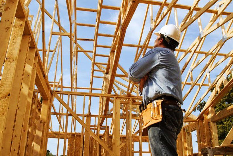 builder in white helmet checking wooden house foundation