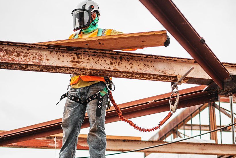 builder in protective helmet carrying a wooden plank