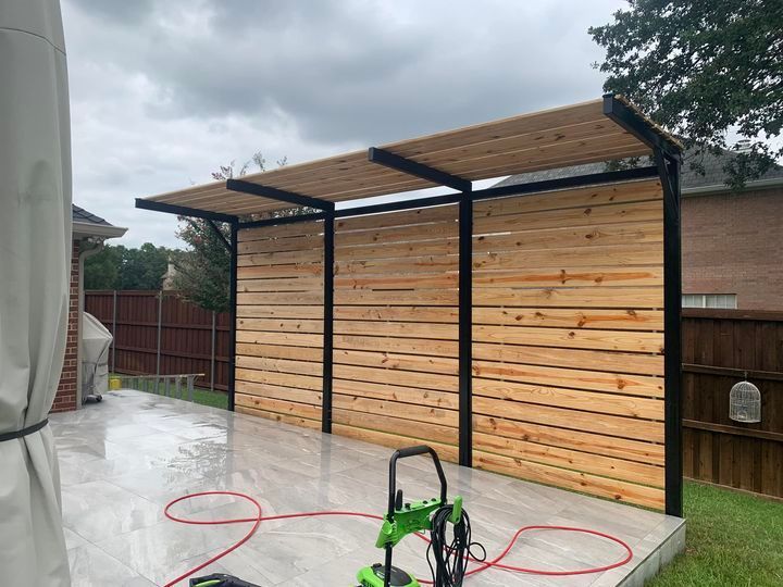 Patio with wooden wall and awning; a pressure washer on the wet ground.