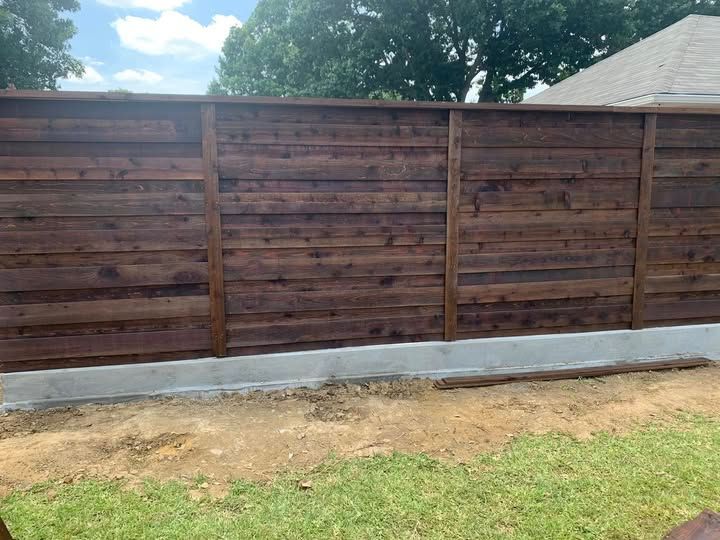 A wooden fence is in the backyard of a house.
