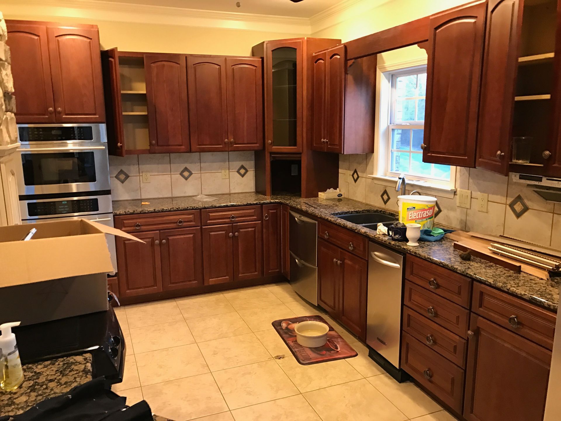 Spacious kitchen with wooden cabinets, tiled floor, granite counters, and a window over the sink.
