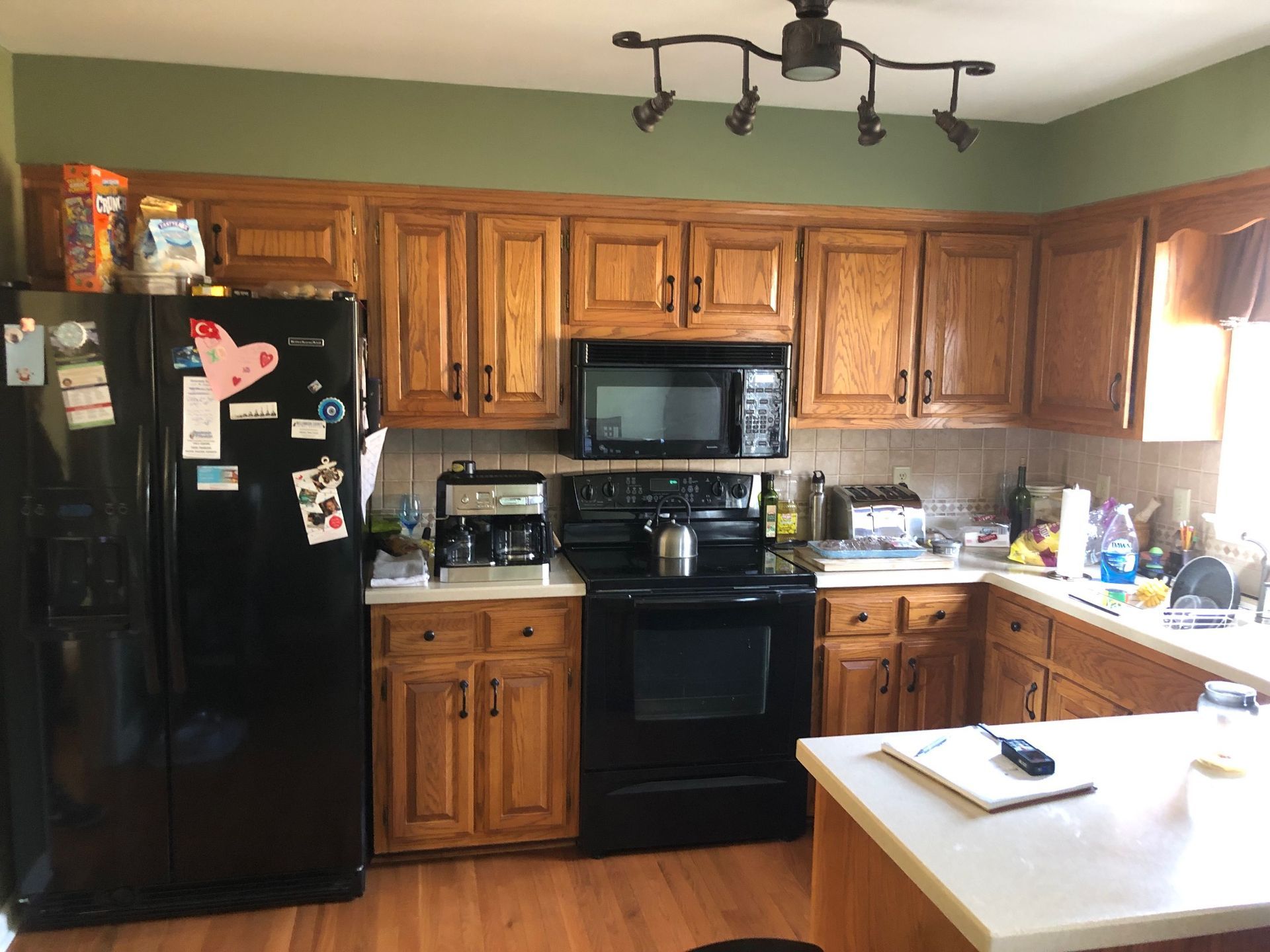 Small kitchen with wooden cabinets, black appliances, and a countertop under bright overhead lights.