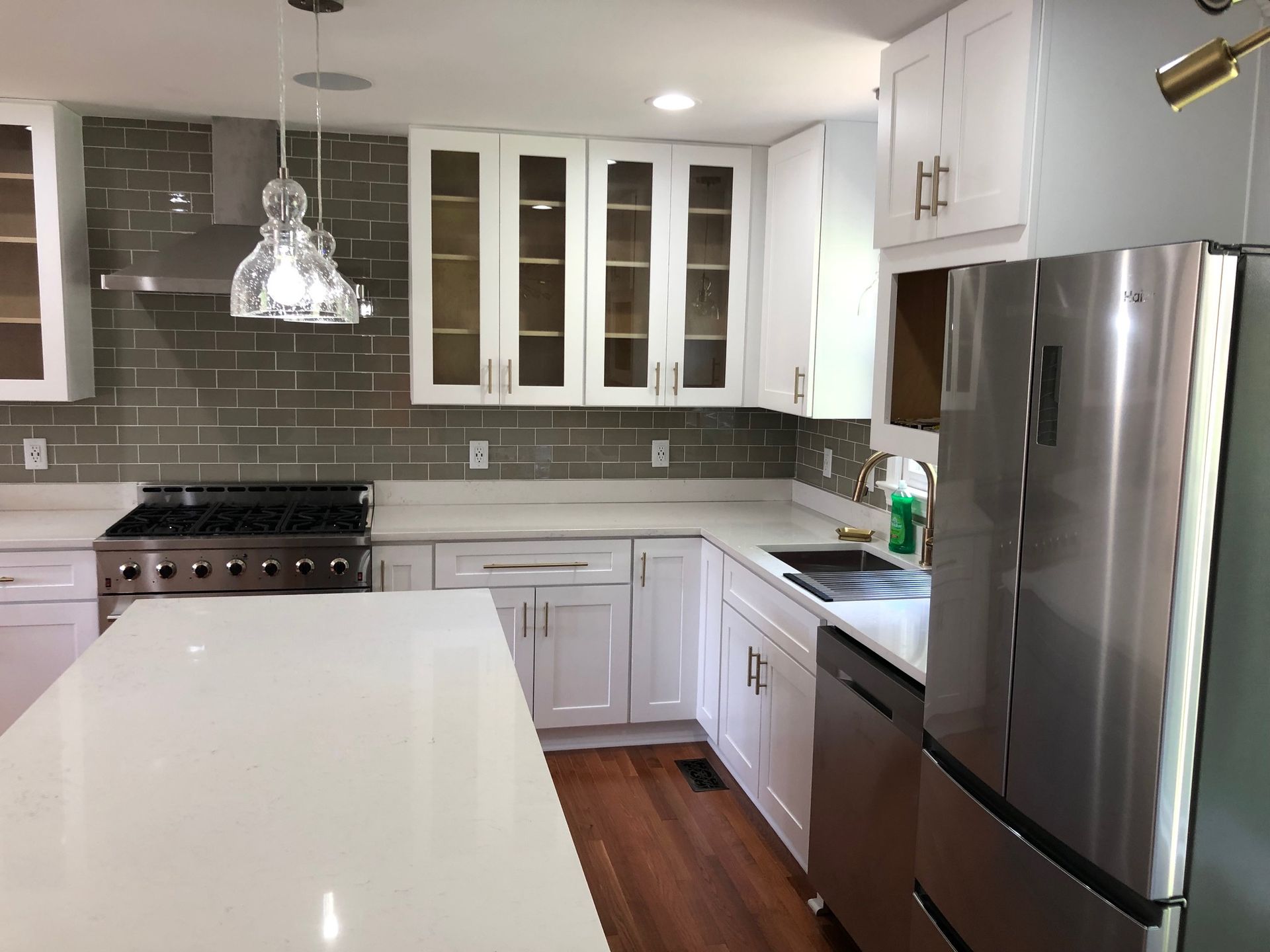 Bright modern kitchen with white cabinets, gray subway tile, stainless steel appliances, and a large island