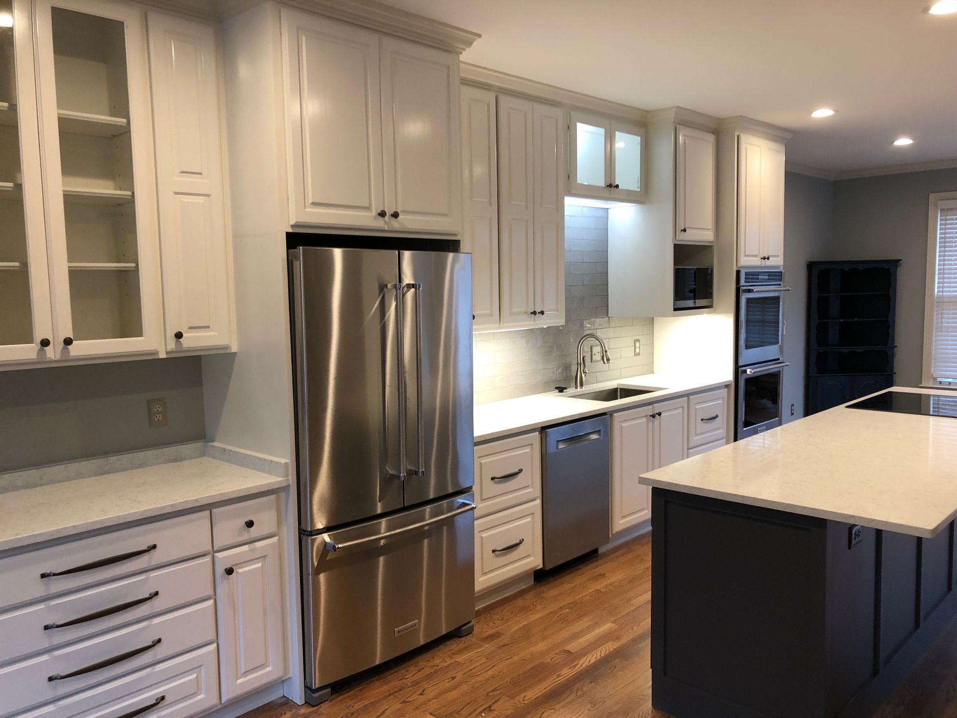 Bright modern kitchen with white cabinets, stainless steel fridge, and dark island