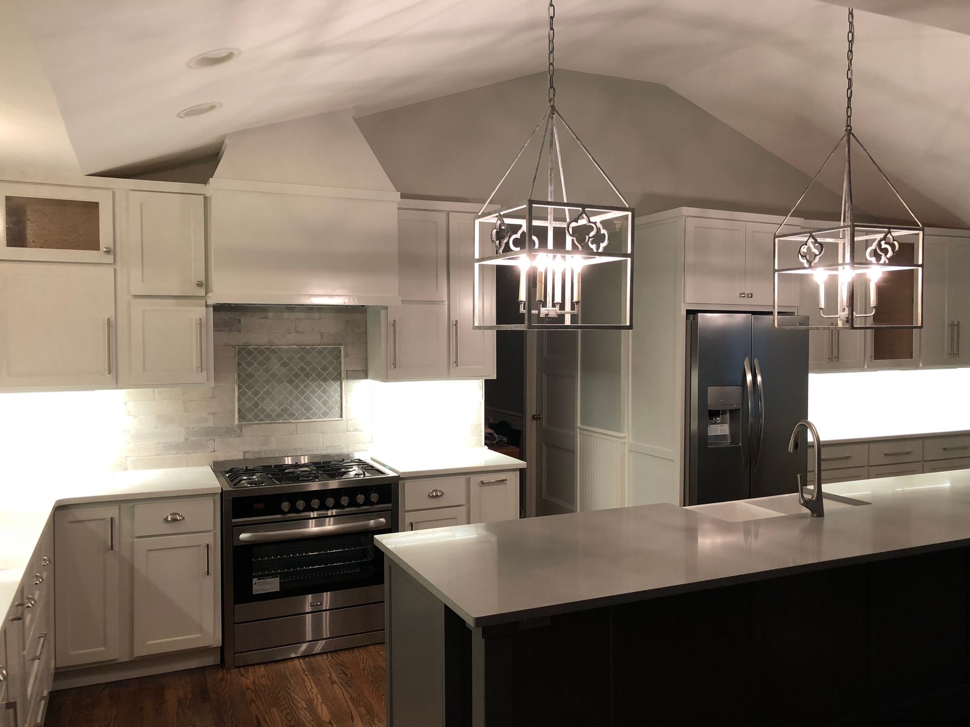 Modern kitchen with white cabinets, stainless appliances, island, and hanging pendant lights