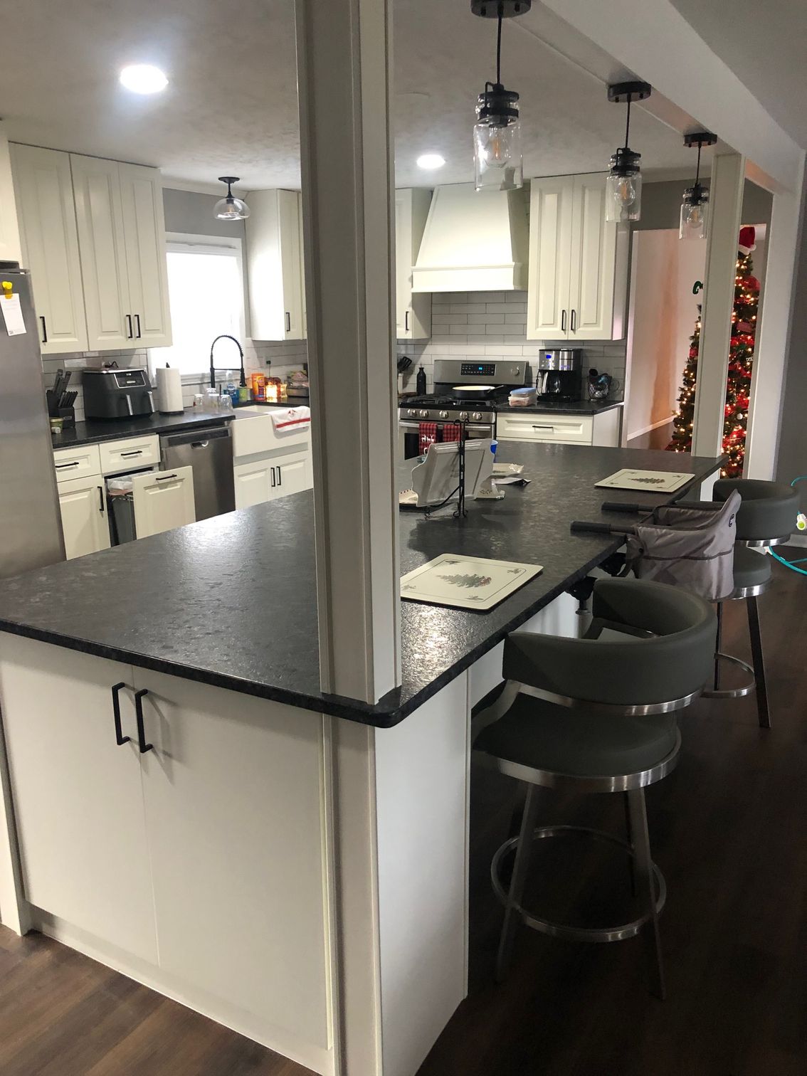 Modern kitchen with white cabinets, dark countertops, island seating, and pendant lights