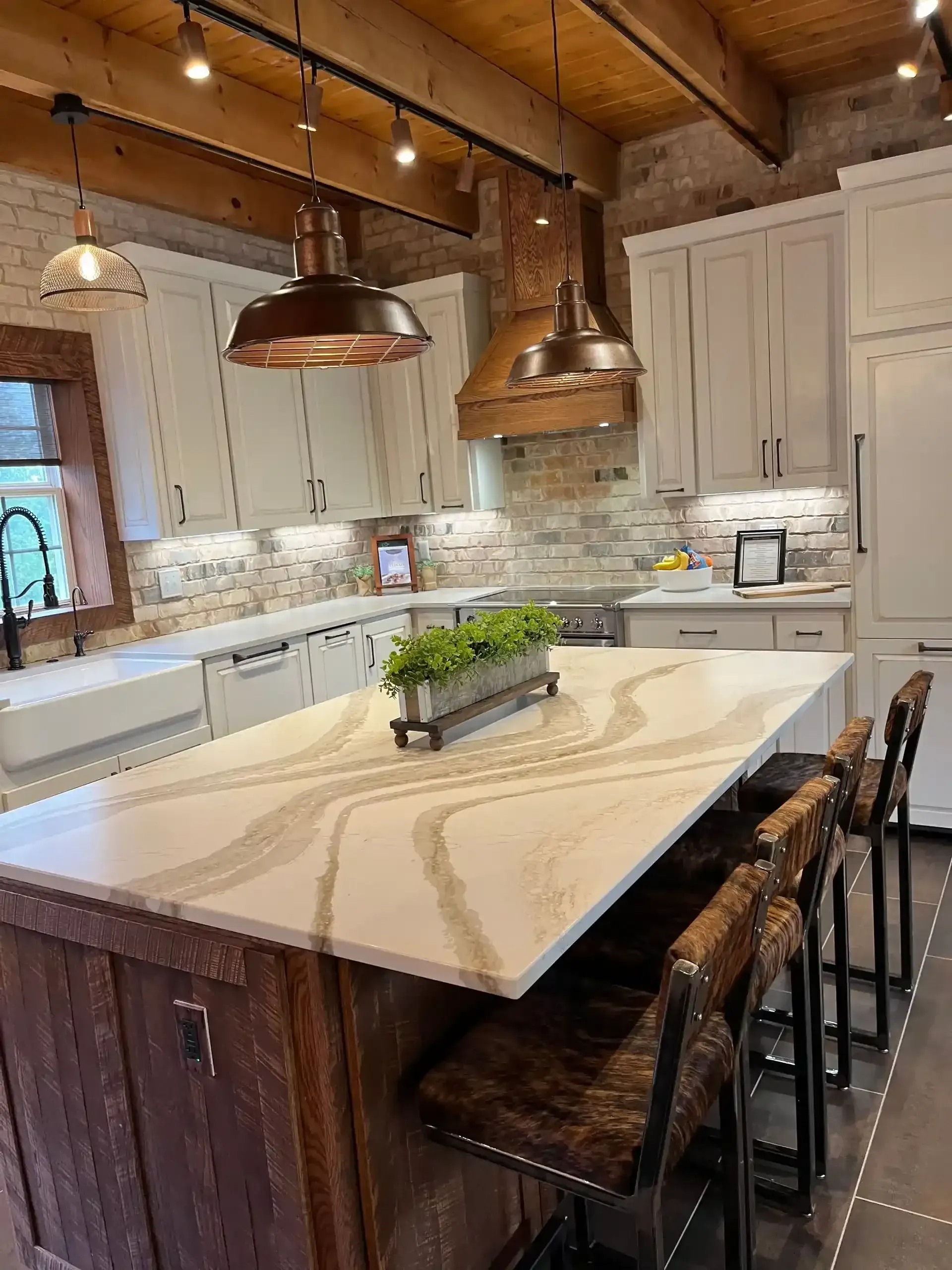 Modern kitchen with white cabinets, large island, wood ceiling, and three bar stools