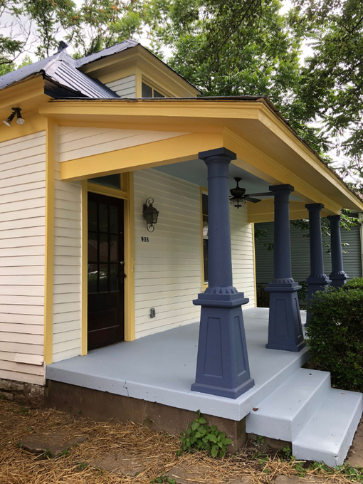Front porch with blue columns and steps on a yellow house, showing an accessible entrance.