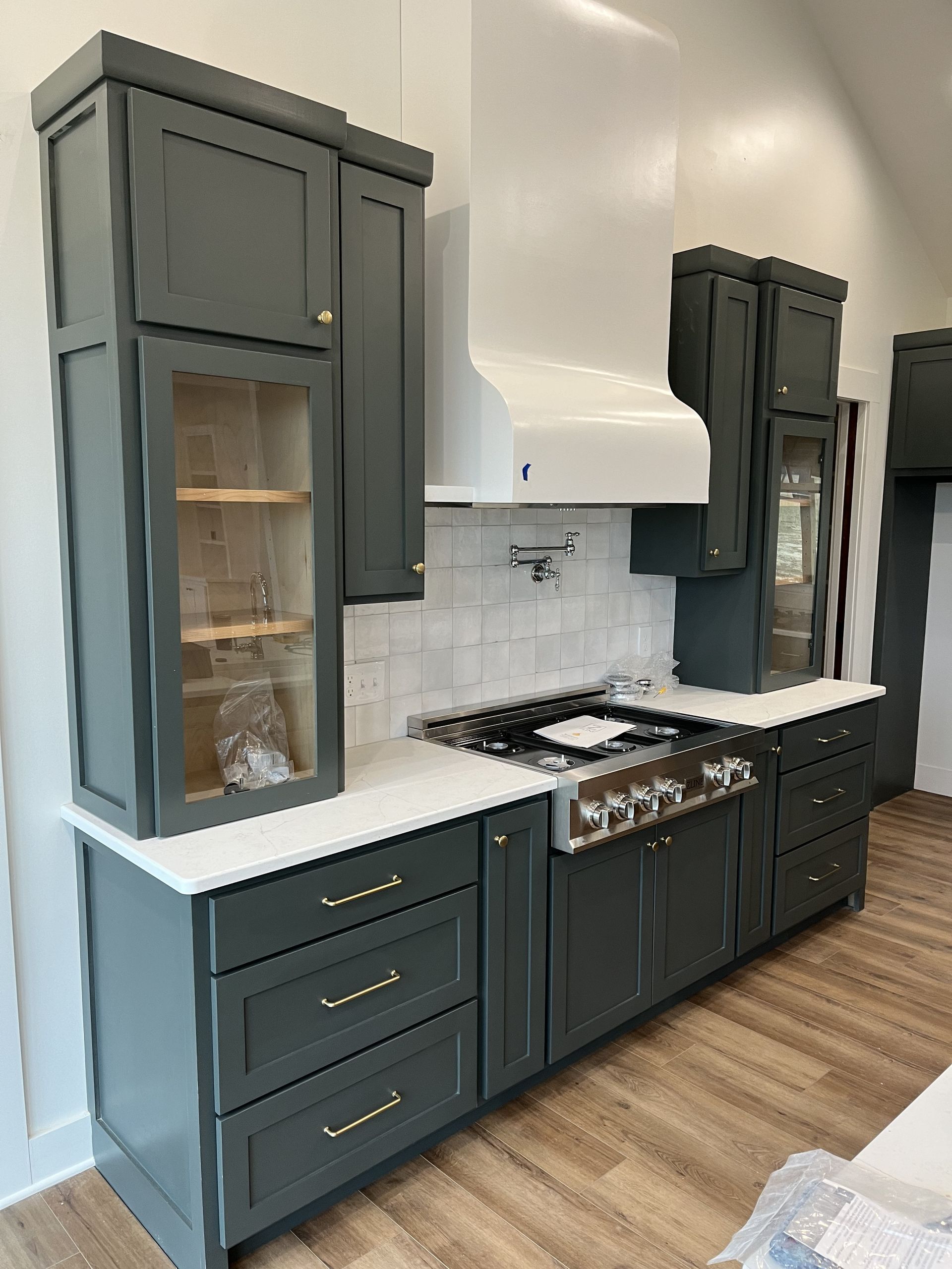 Dark gray kitchen cabinets with white countertops and a gas stove in a modern kitchen