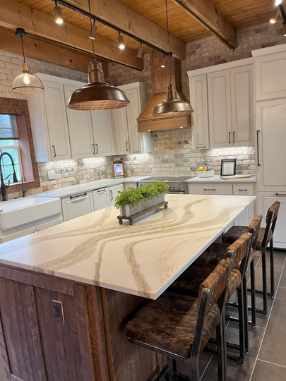 Modern kitchen with large marble island, copper pendant lights, white cabinets, and wood ceiling