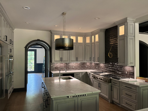 Modern kitchen with a large island, pendant lights, gray cabinets, and a tiled backsplash