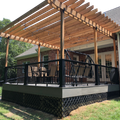 Covered wooden deck with black railing and pergola attached to a house