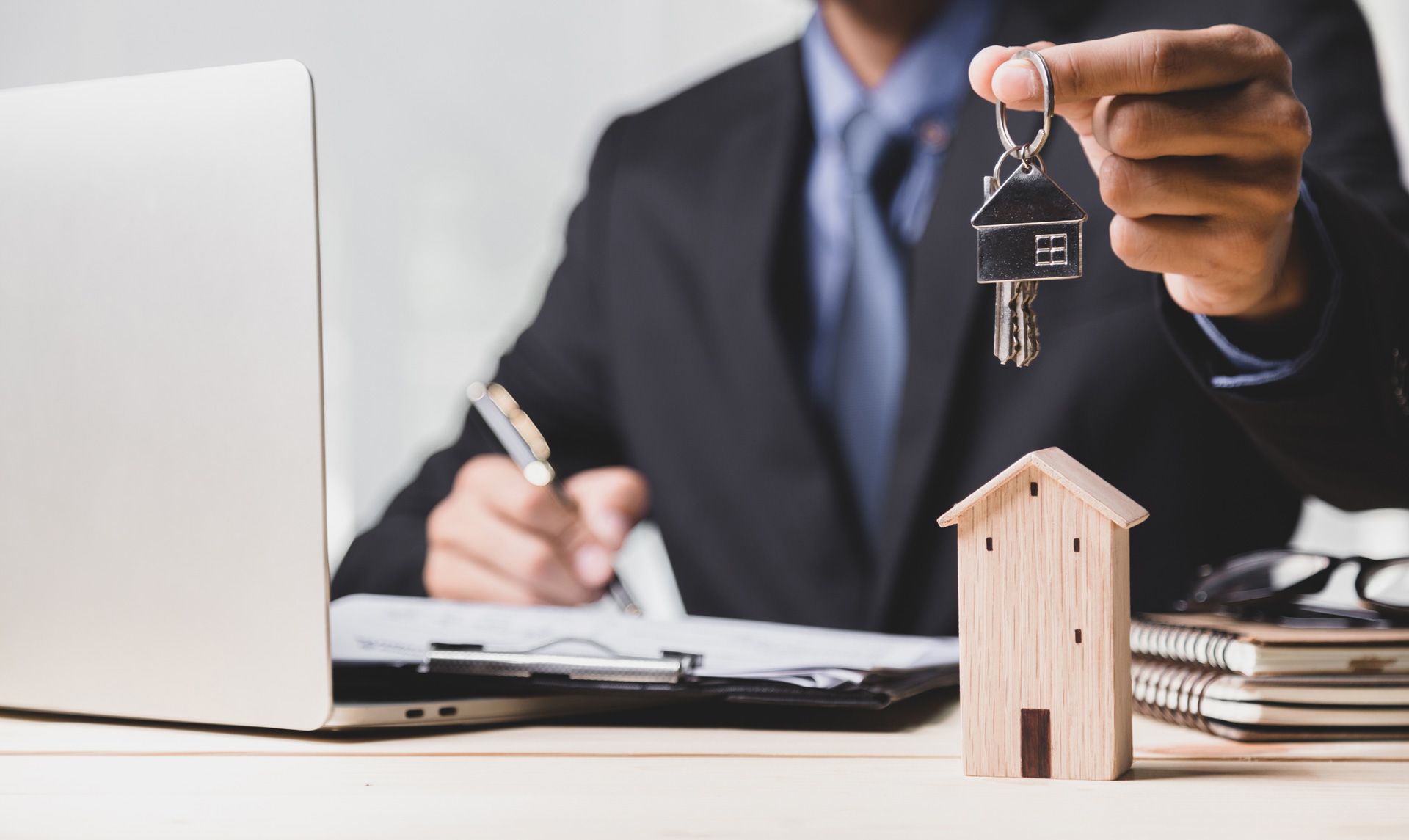 A Man Holding a Key with a Miniature House on the Table | Brisbane Qld | Mta-More Than Accountants Pty Ltd