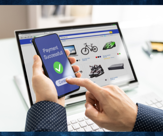 Person holding phone showing payment successful over online shopping site on laptop.