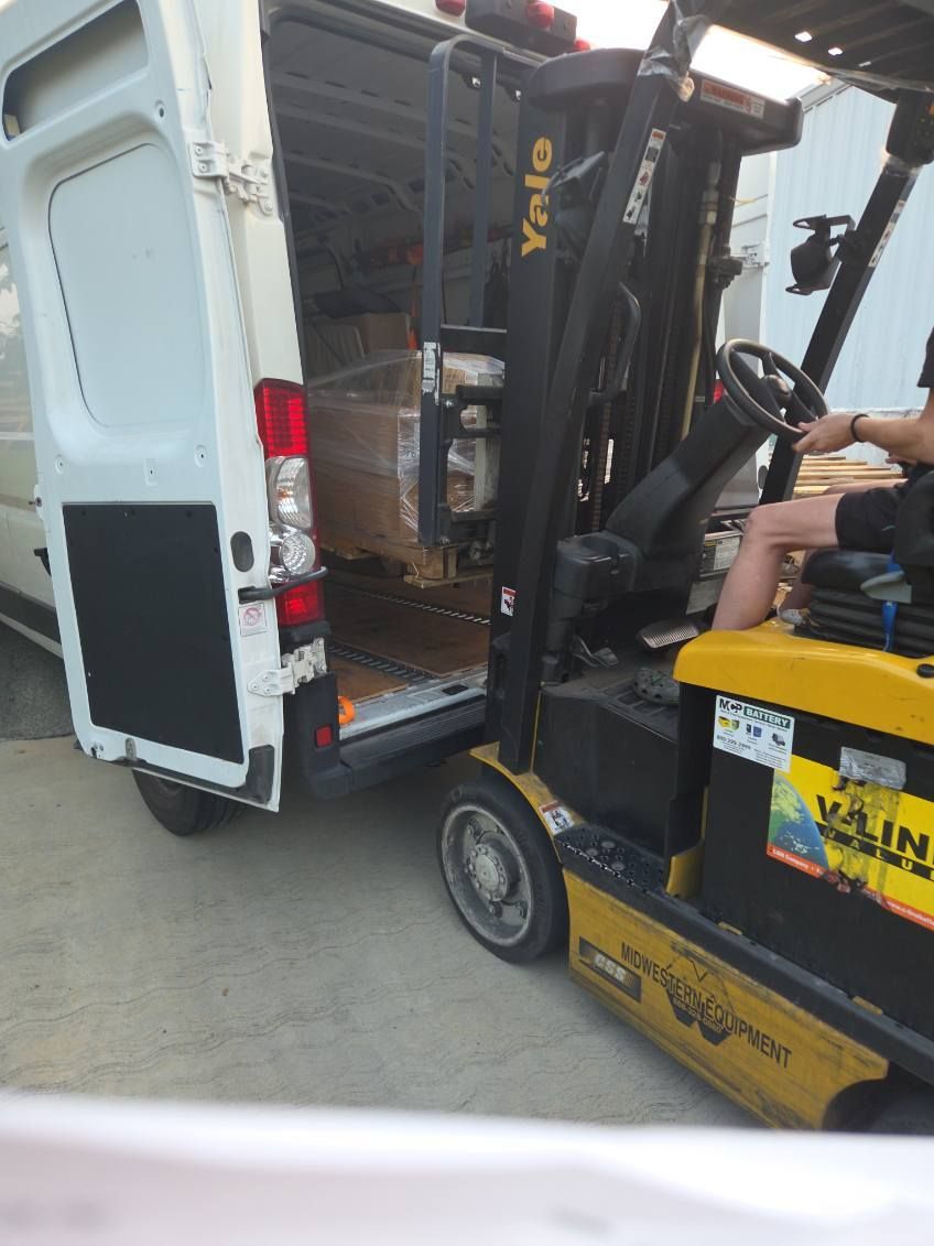 Yellow forklift loading a white delivery truck at a warehouse loading dock