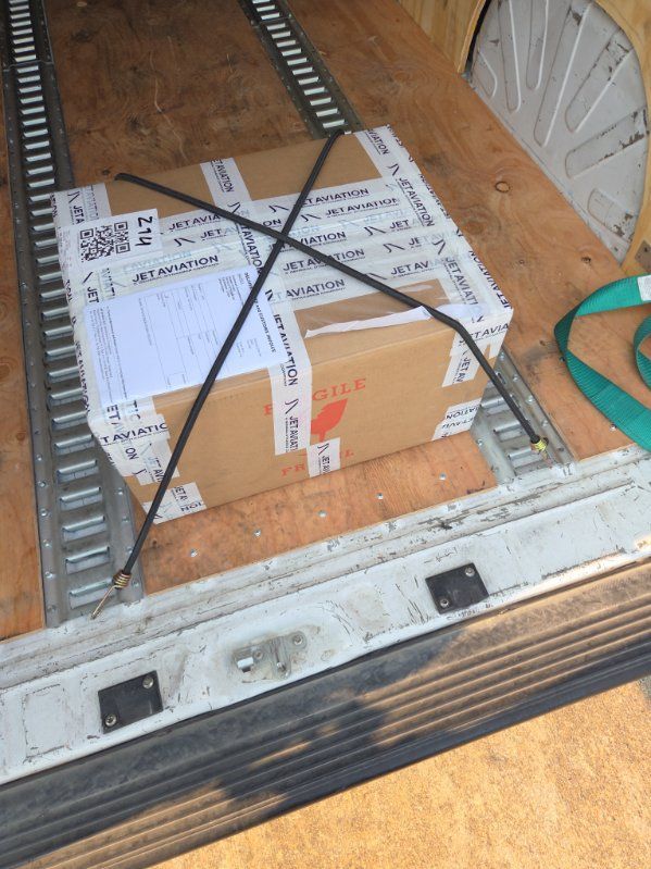 Cardboard boxes strapped with black X-tape inside a truck or cargo trailer.