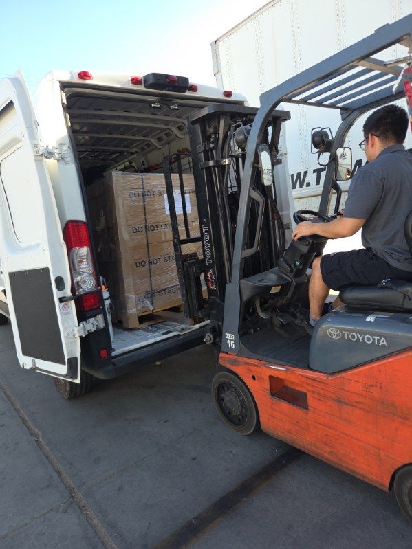 Orange Toyota forklift loading boxes into a white delivery truck