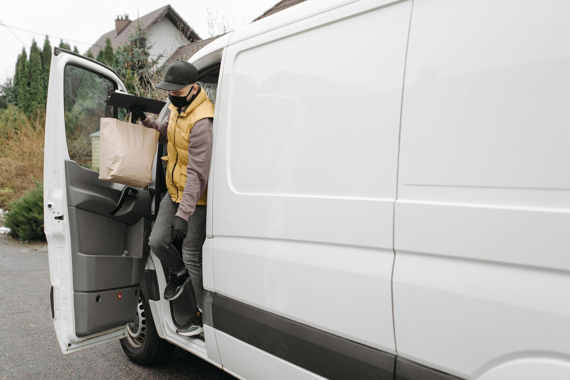 Person stepping out of a white delivery van carrying packages