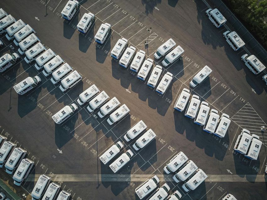 Aerial view of many white camper vans arranged in a large parking lot.