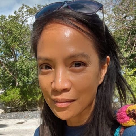 Cecilia Pagkalinawan with sunglasses on her head, smiling outdoors. Natural light, trees in the background.