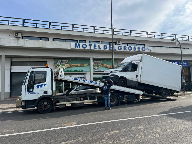 Un carro attrezzi carica un furgone bianco davanti al cartello