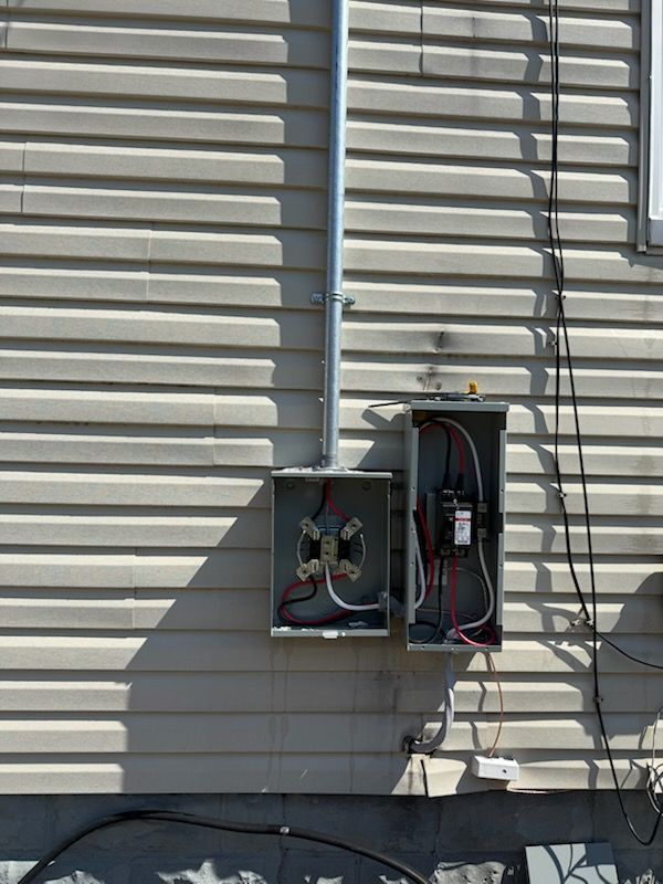 Gloved hand wiring a breaker panel with colorful cables and circuit modules in an electrical box