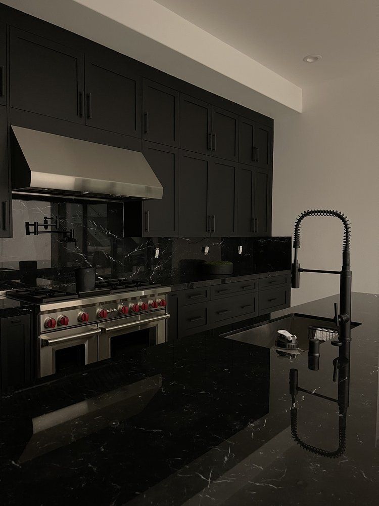 A kitchen with black cabinets and stainless steel appliances