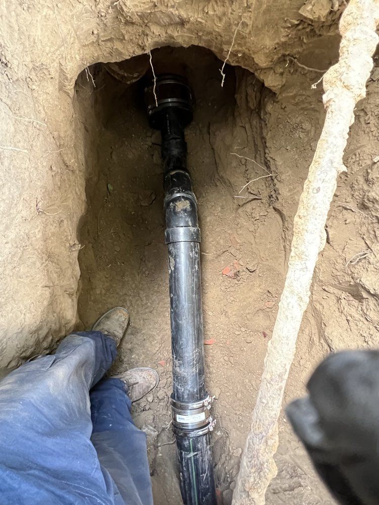 A person is standing next to a pipe in the dirt.