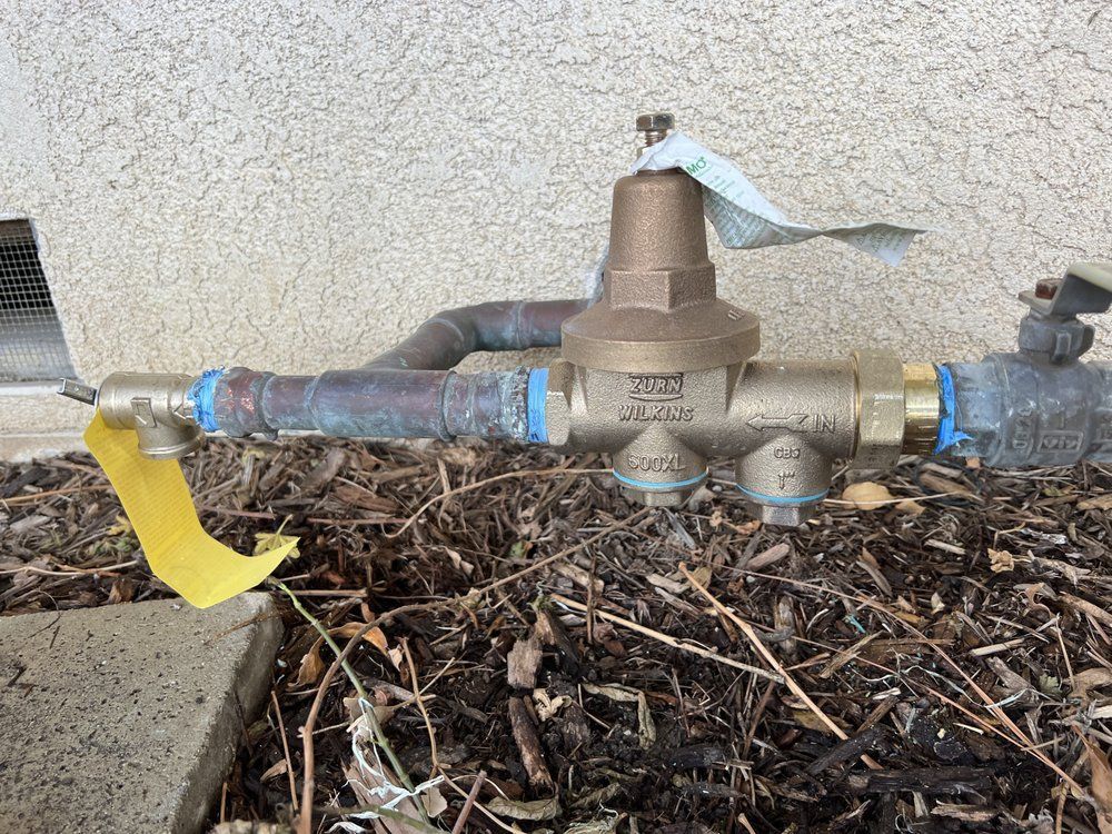 A water valve is sitting on the ground next to a wall.