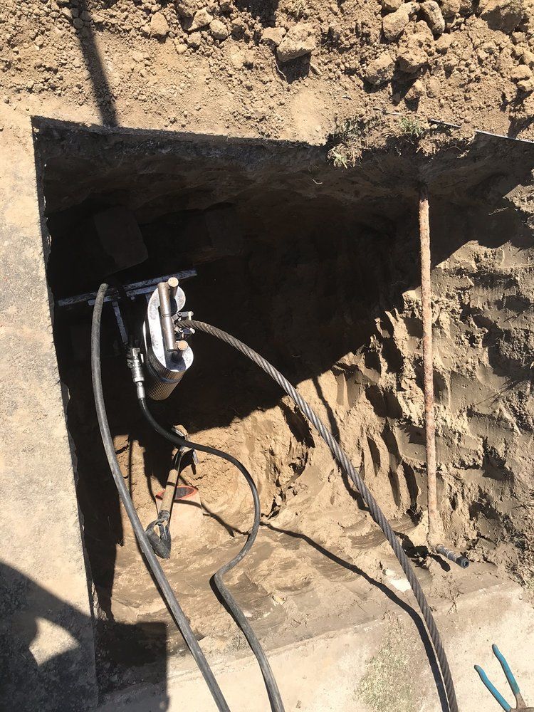 A hole in the ground with a bunch of wires coming out of it