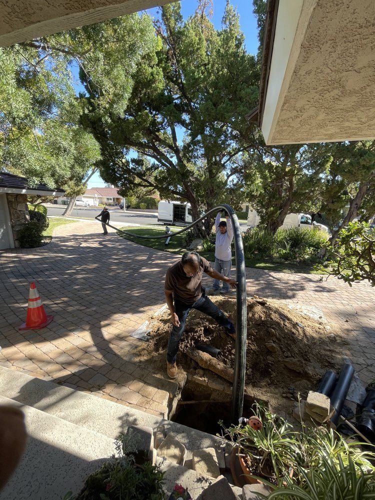 A man is digging a hole in the ground in front of a house.
