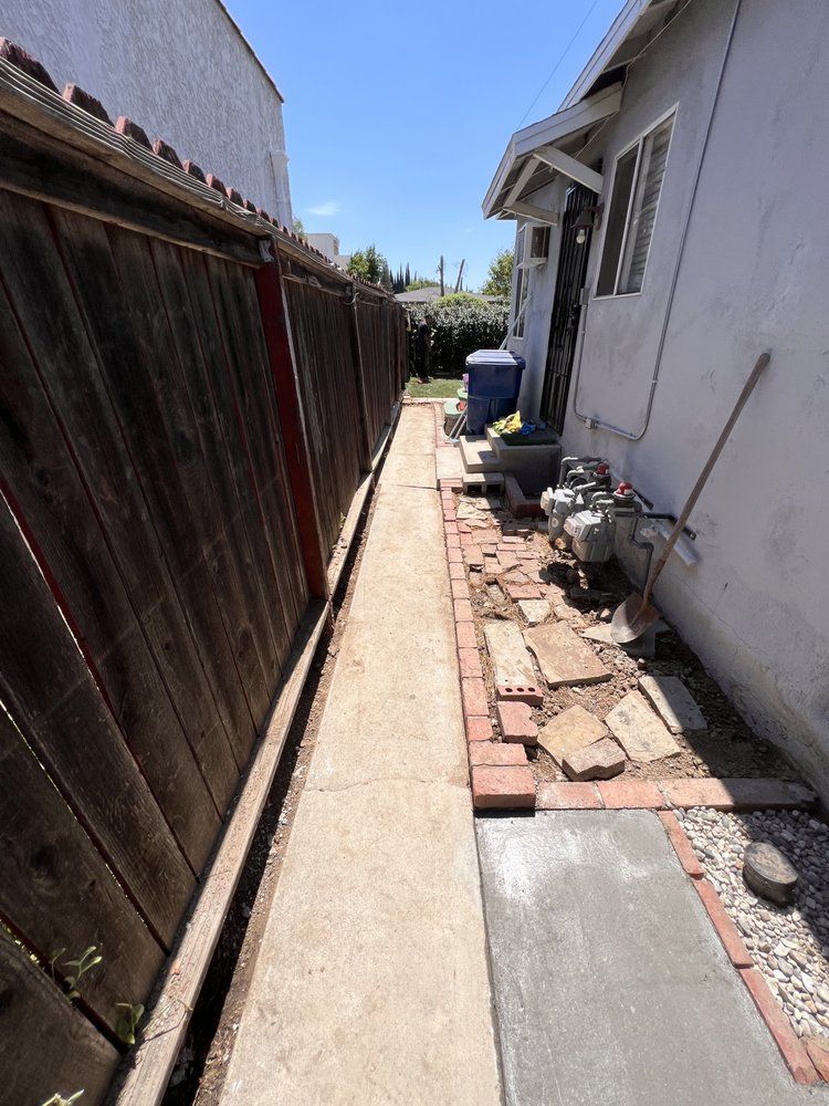 A brick walkway is being built in the backyard of a house.