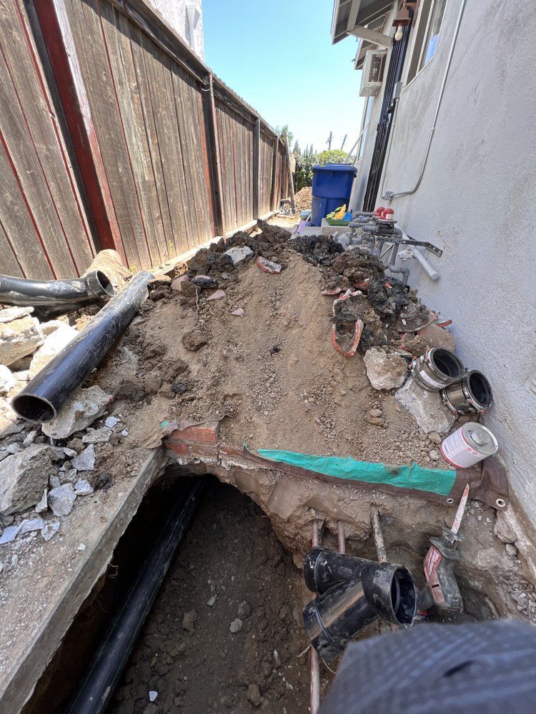 A person is digging a hole in the ground next to a fence.