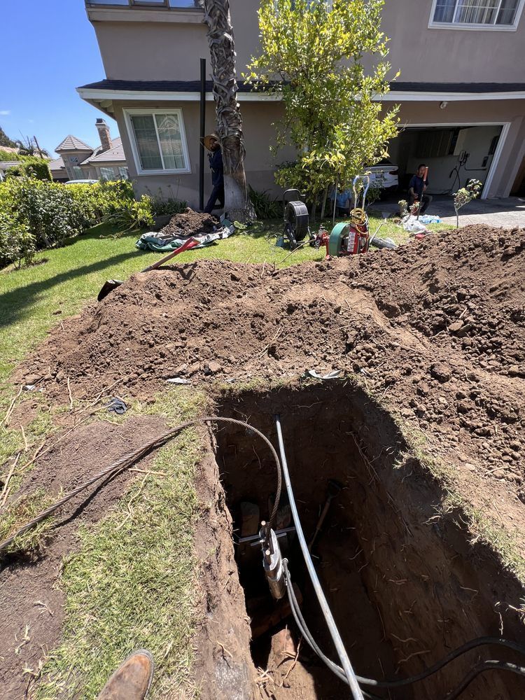 A man is digging a hole in the ground in front of a house.