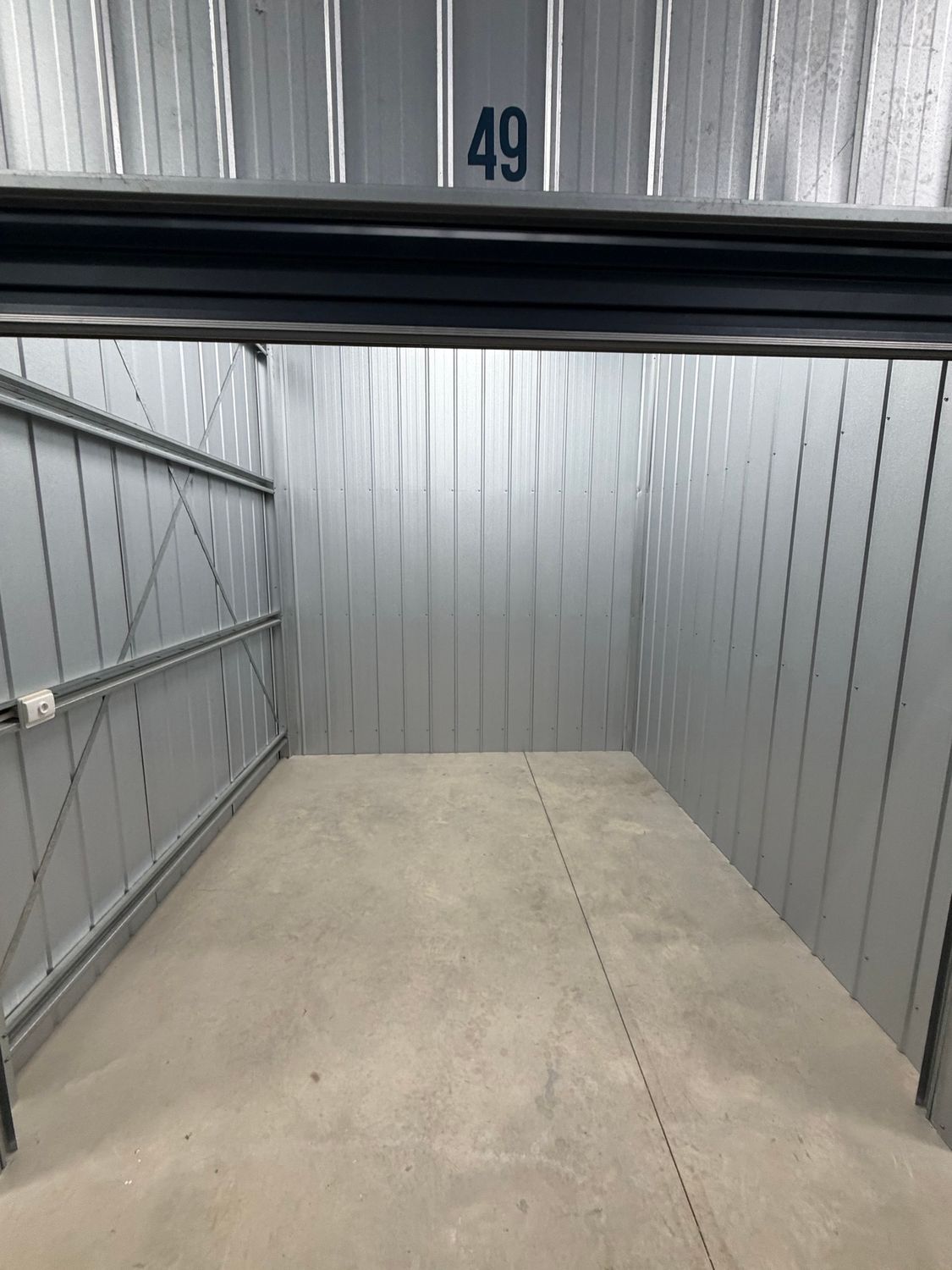 Empty storage unit numbered 49 with gray walls and a concrete floor.
