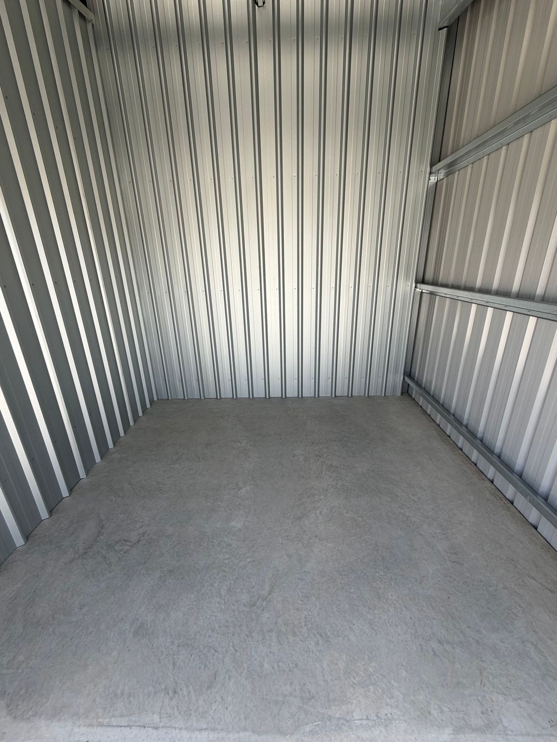 Empty storage hallway with blue roll-up doors and bright overhead lights