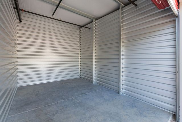 Empty metal storage unit with ribbed white walls and a concrete floor