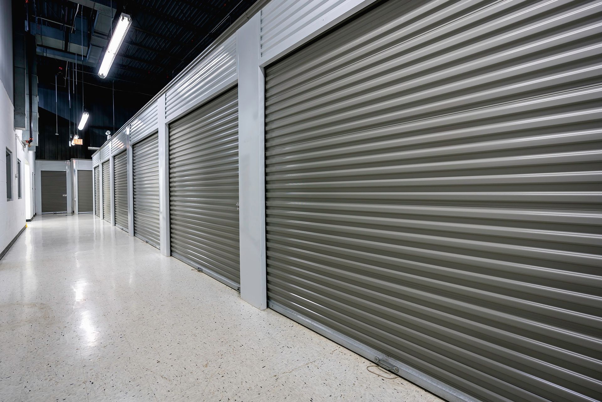 Indoor hallway with closed gray metal storage unit doors and a polished floor