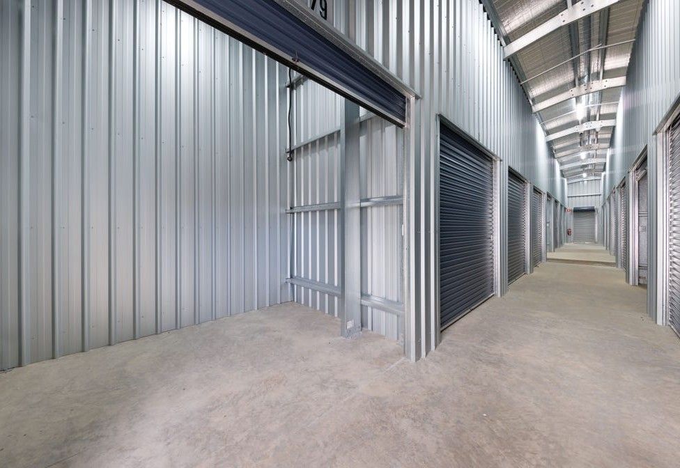 Row of blue roll-up storage doors along a white industrial building