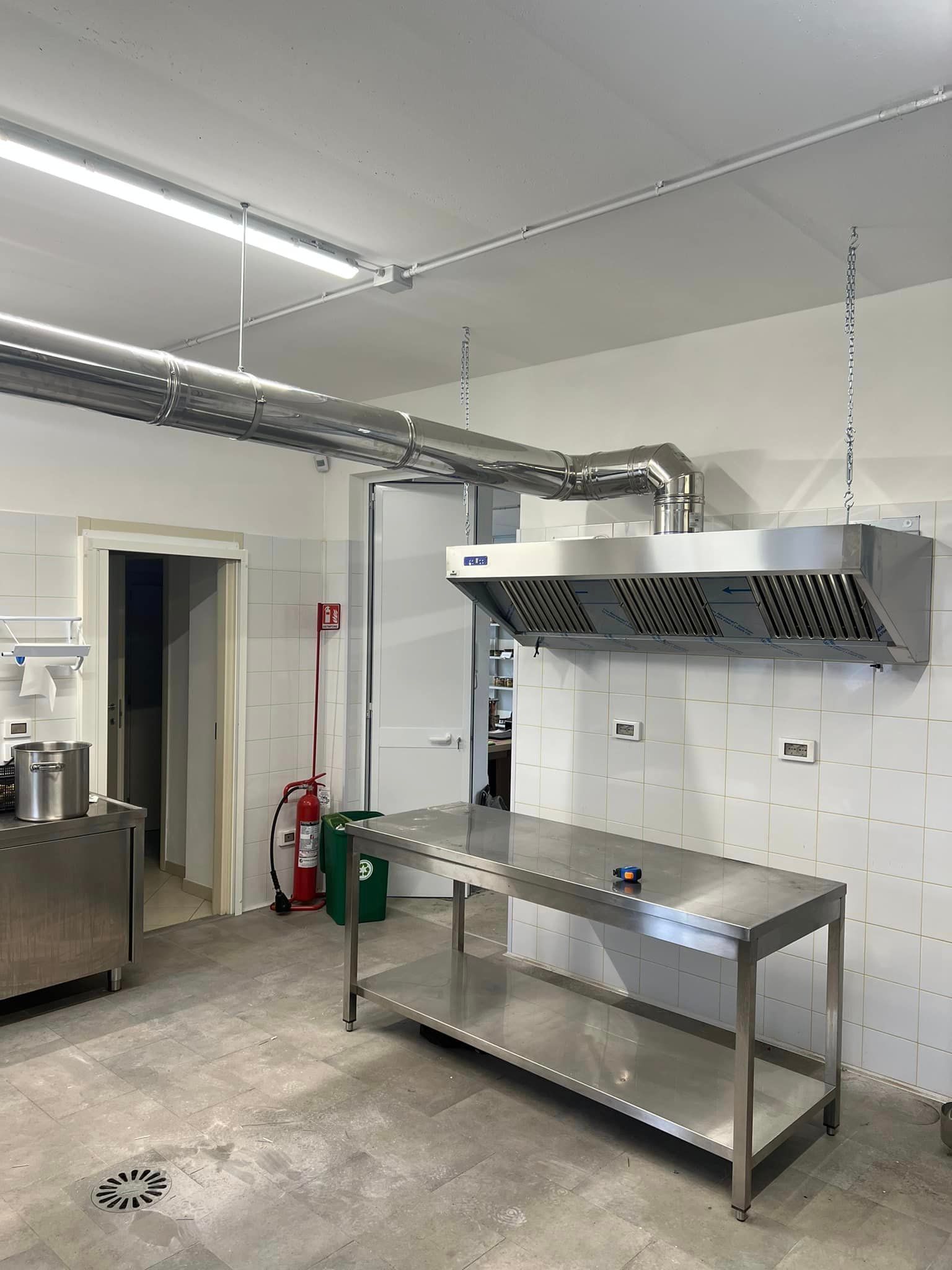 una cucina con tavolo in acciaio inox ed estintore