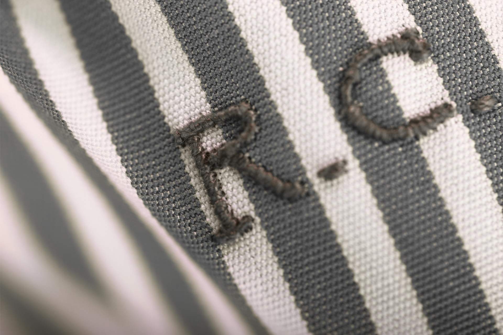 Close-up of a striped fabric with embroidered letters “R.C.”