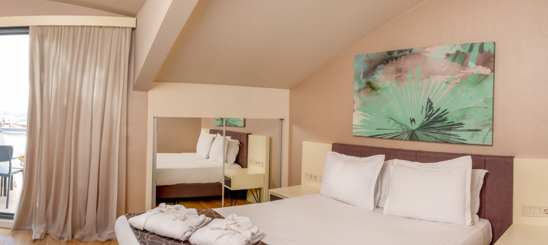 A hotel bedroom with a large bed, balcony access, and artwork. 