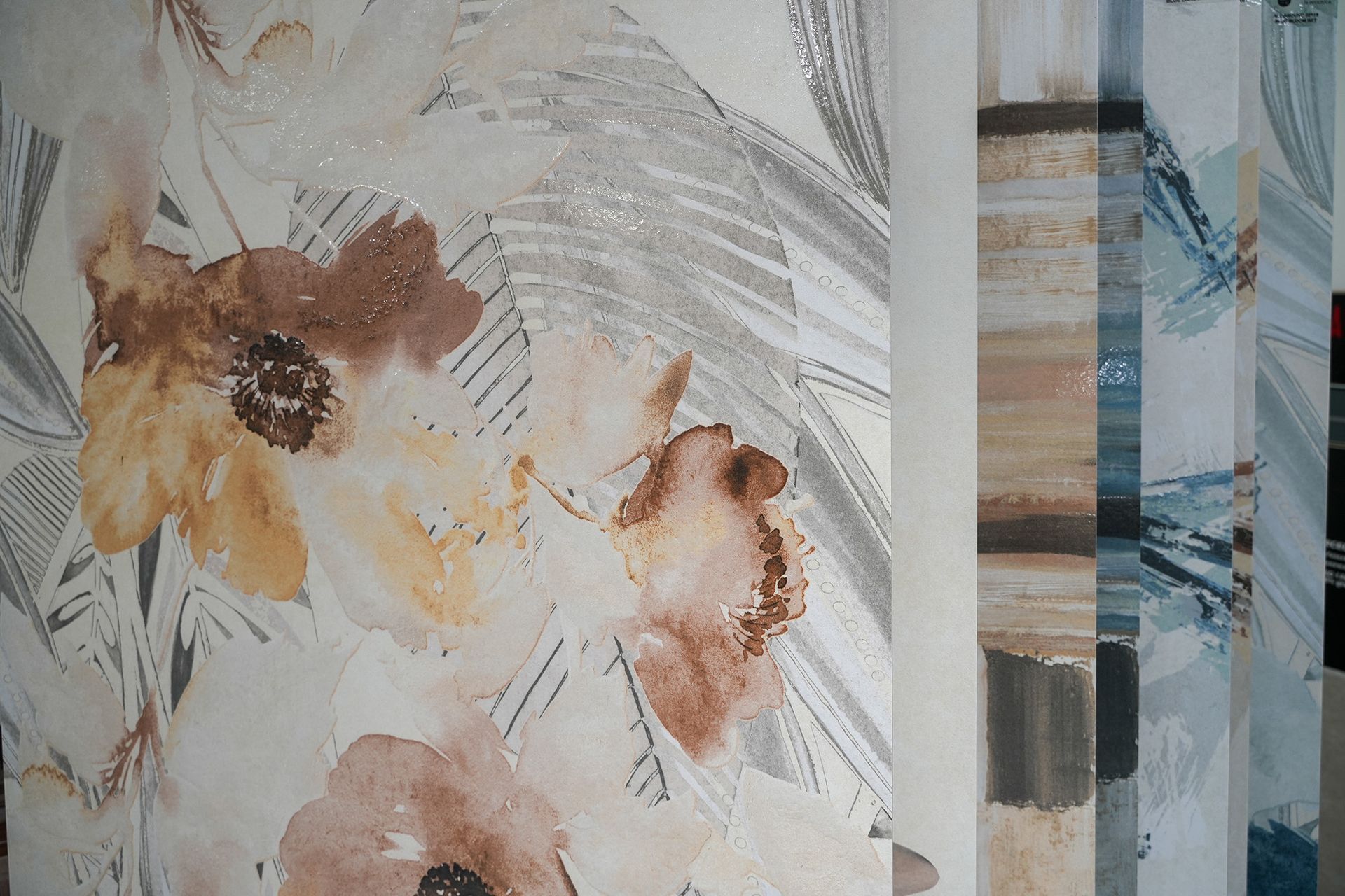 Una composizione verticale di campioni di tessuto con motivi floreali ad acquerello nelle tonalità del marrone, beige, blu e grigio.