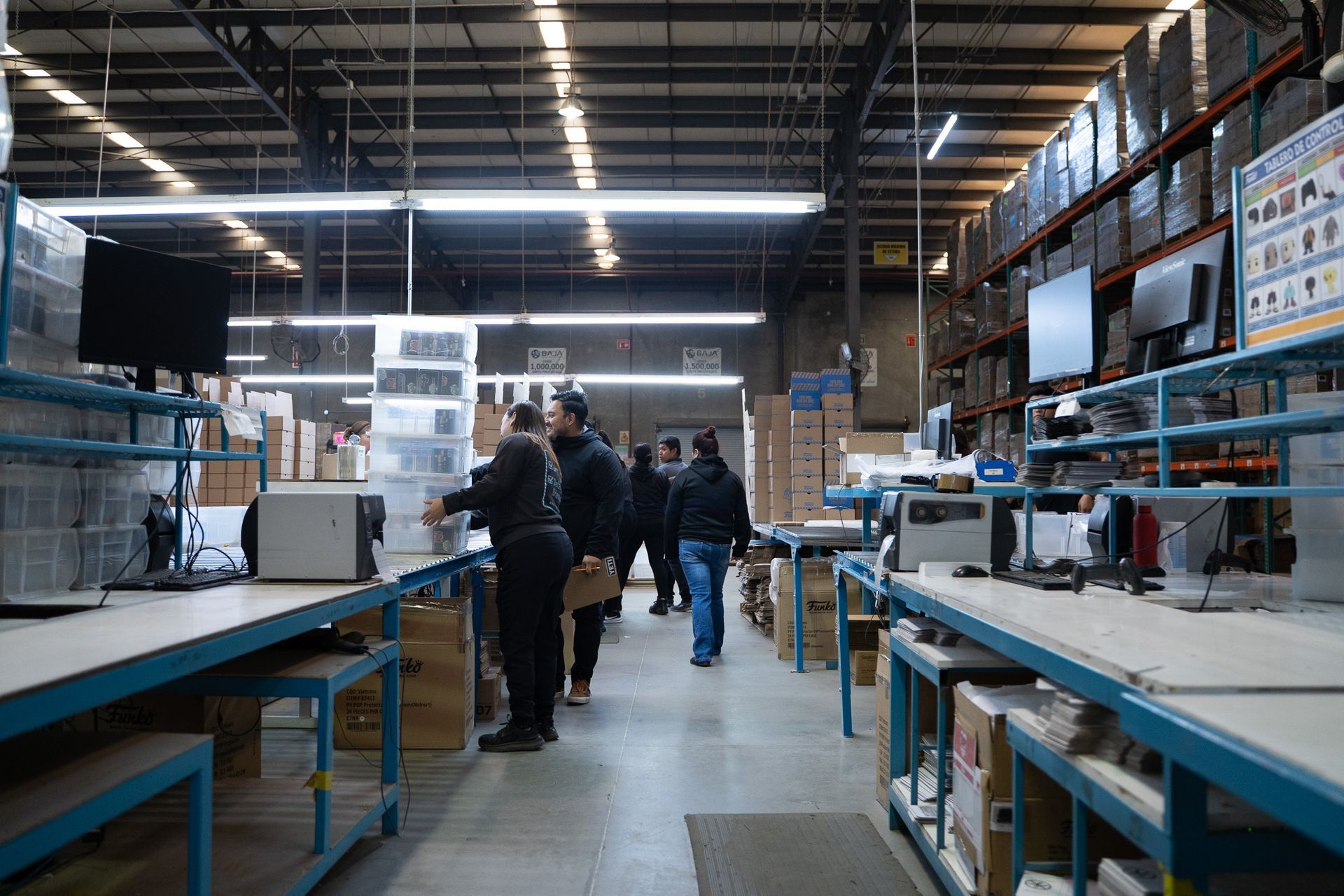People browsing shelves in a warehouse-style store with tables, boxes, and overhead lights