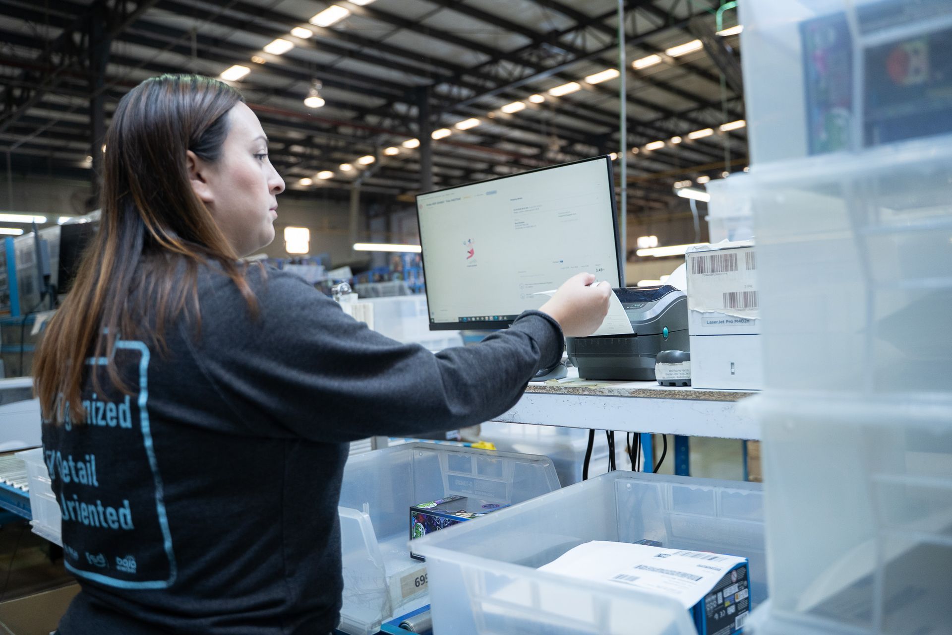 Worker scanning items on a warehouse conveyor line amid shelves and bins
