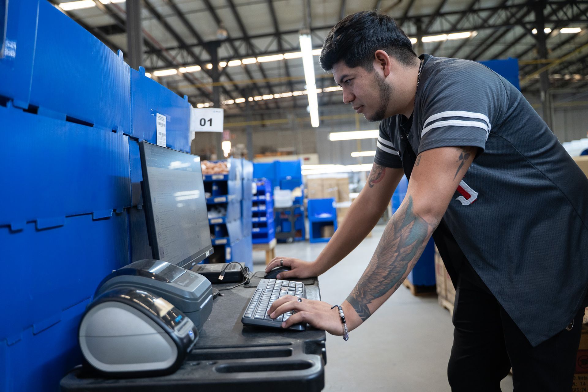 Man in a warehouse packing a printer on a table near blue storage units