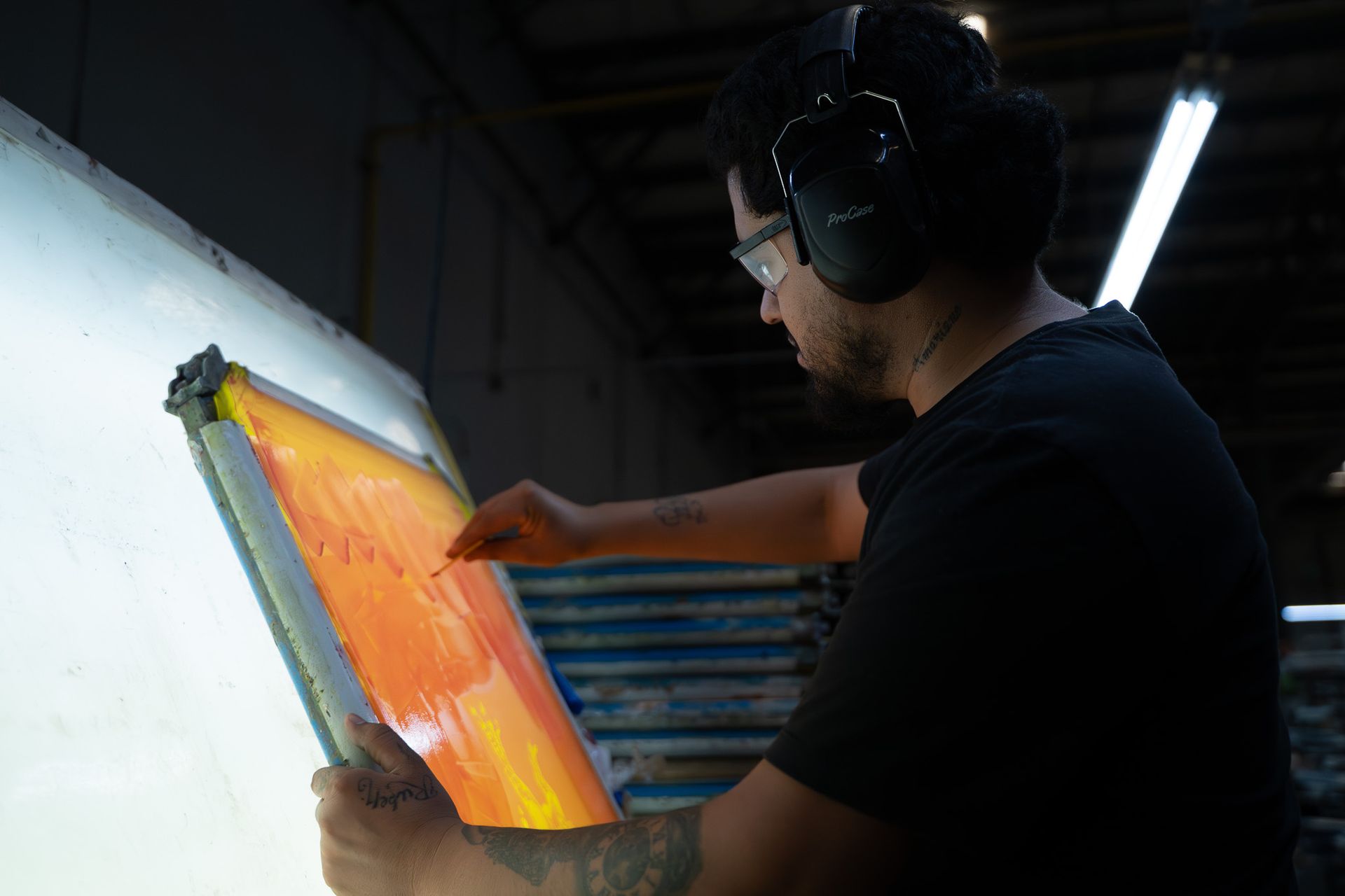 Person using a squeegee to print orange ink on a screen in a workshop
