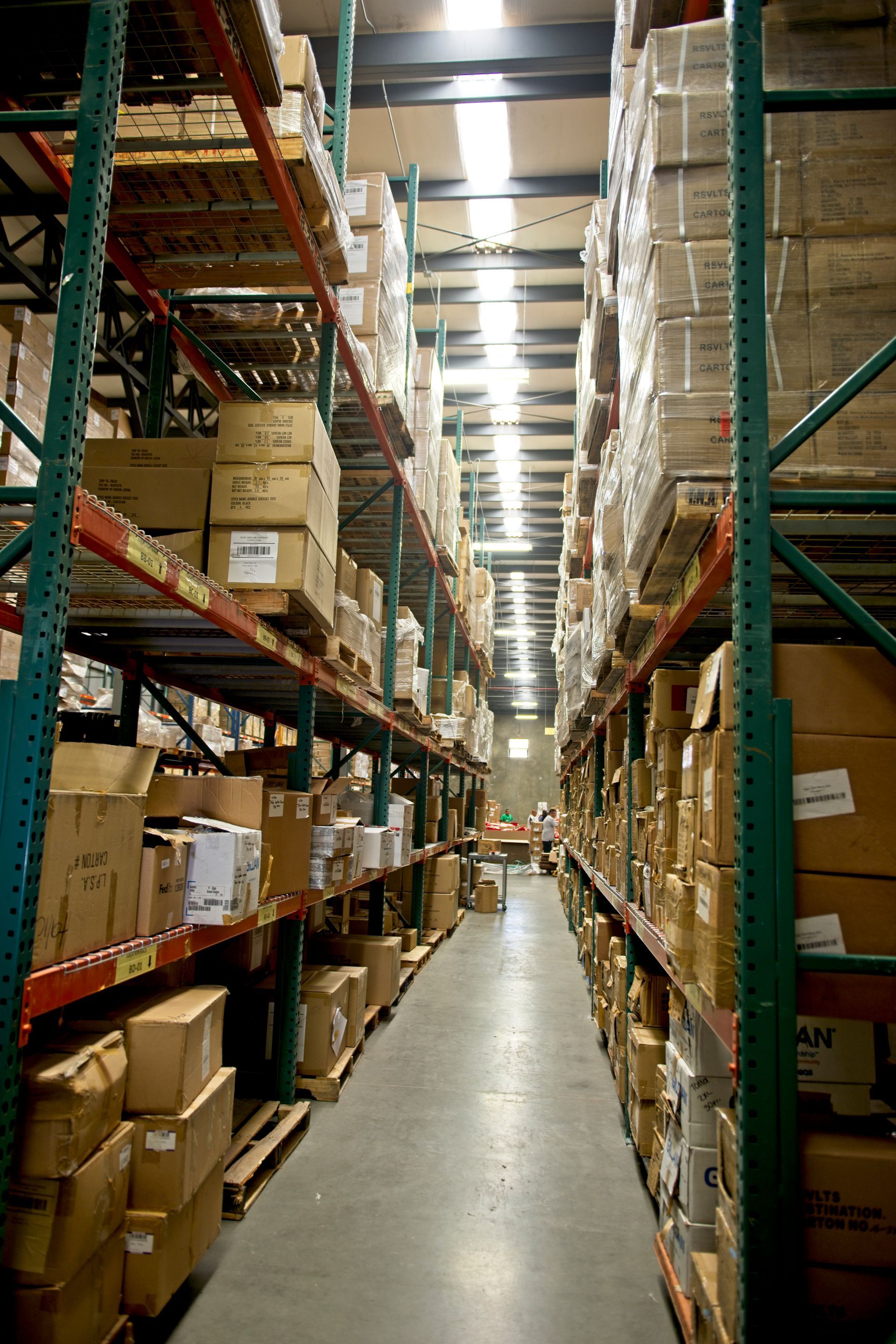 Warehouse aisle with tall racks of boxes and parcels stacked on both sides