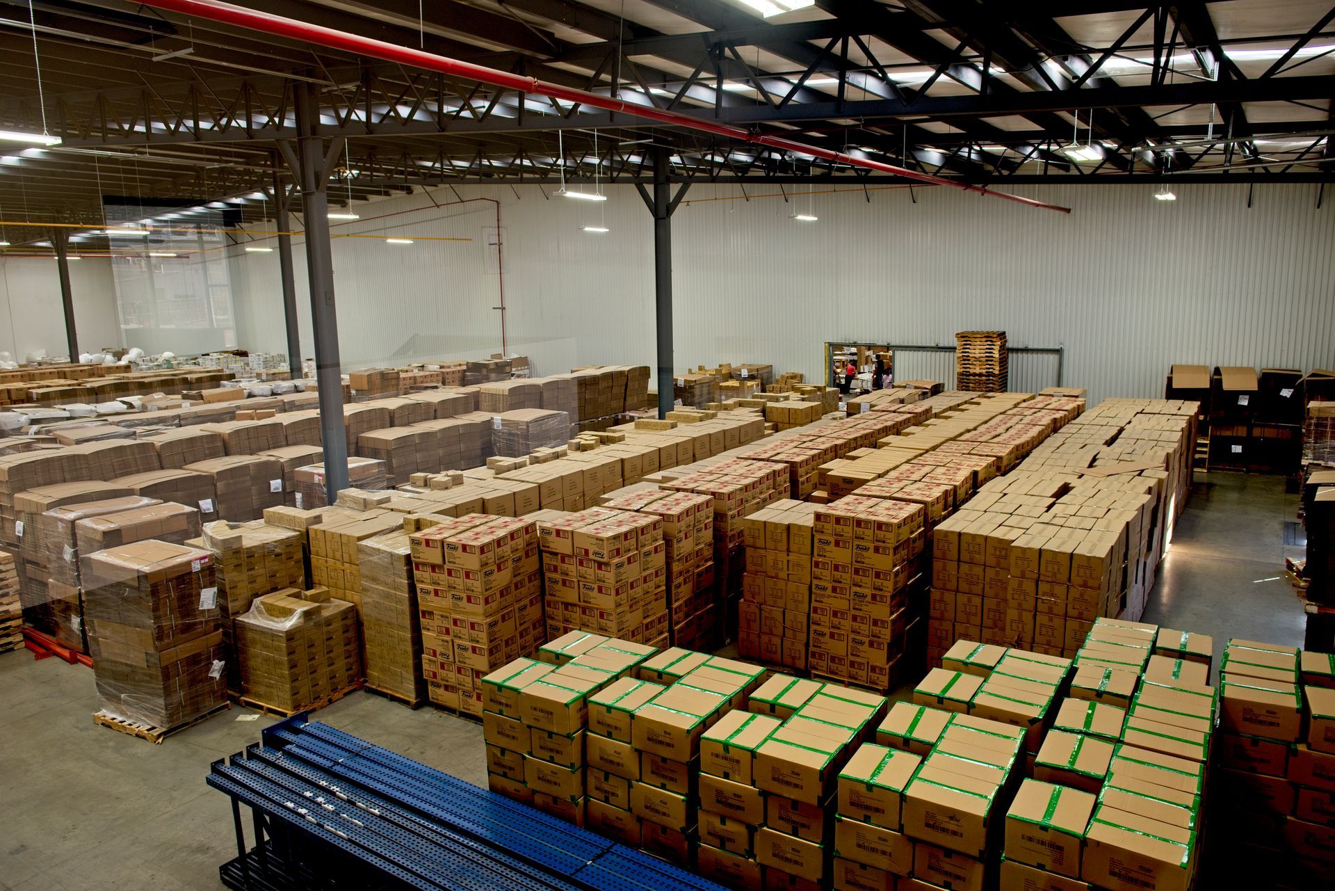 Warehouse packed with stacked cardboard boxes on pallets under industrial ceiling lights