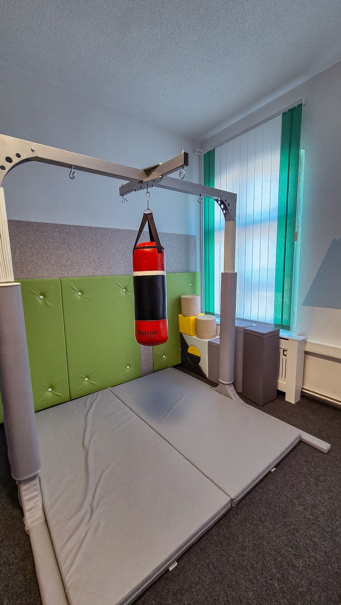 Kinderzimmer mit einem hängenden roten Boxsack und einem Spielgerüst am Fenster